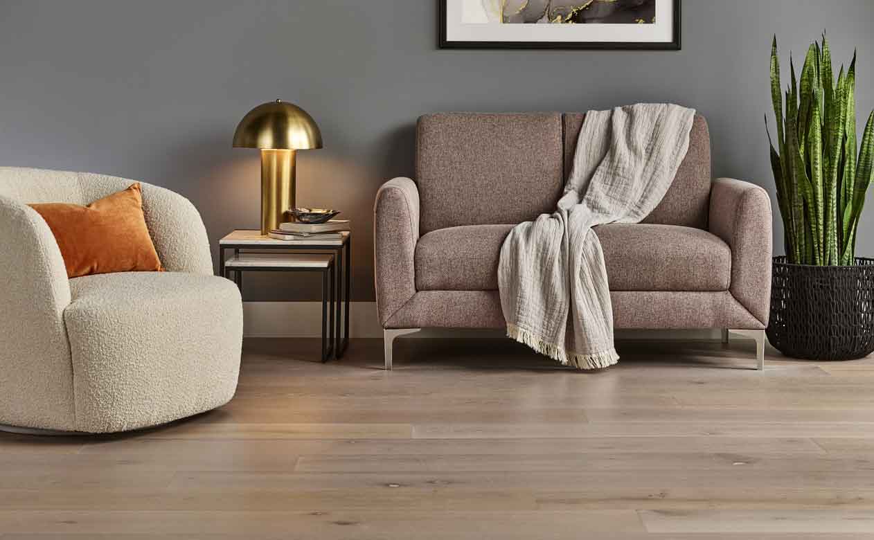 Hardwood floors in a living room with a brown sofa and beige accent chair